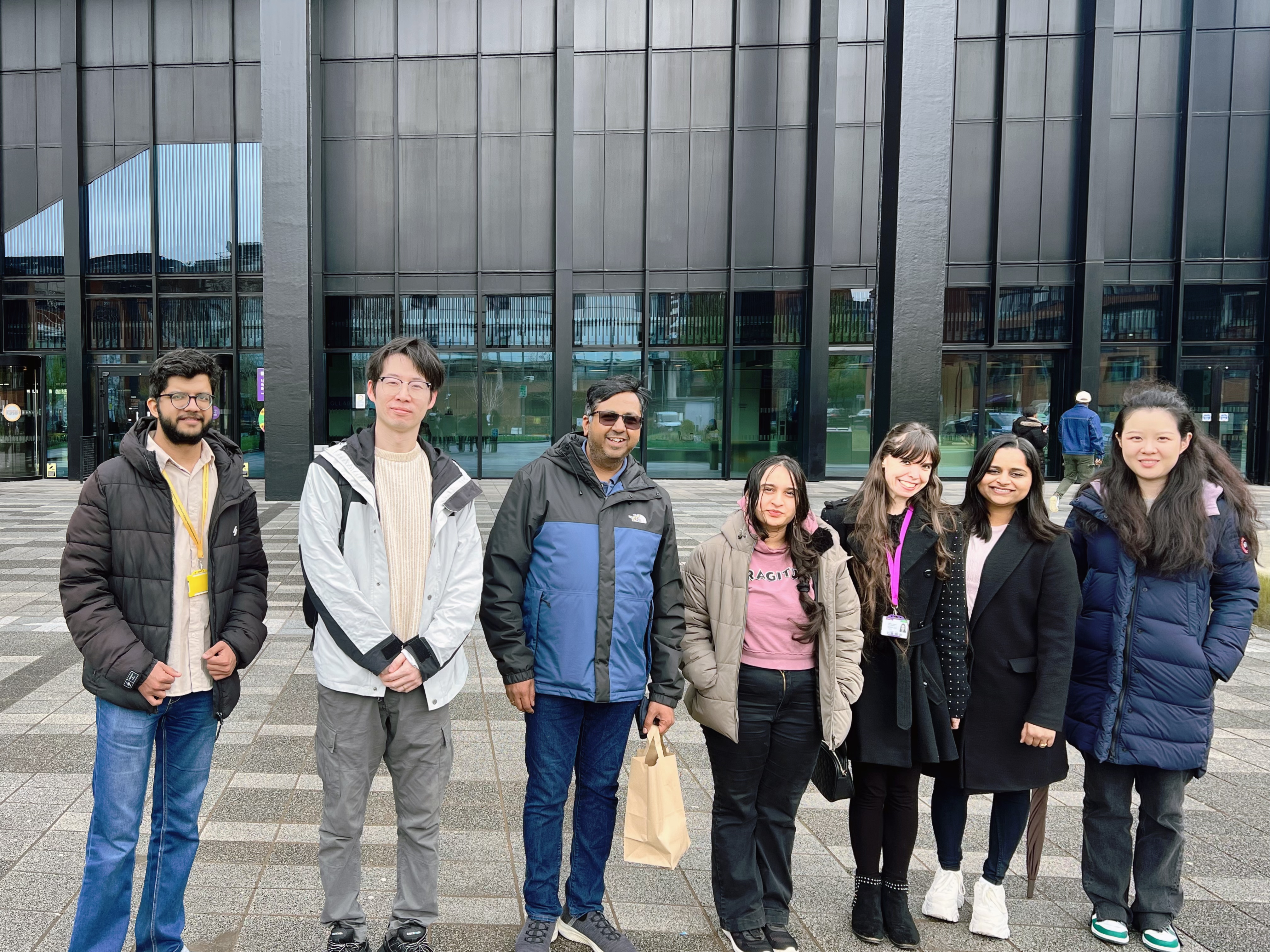Seven members of the lab group standing together outside a university building before the celebration lunch.